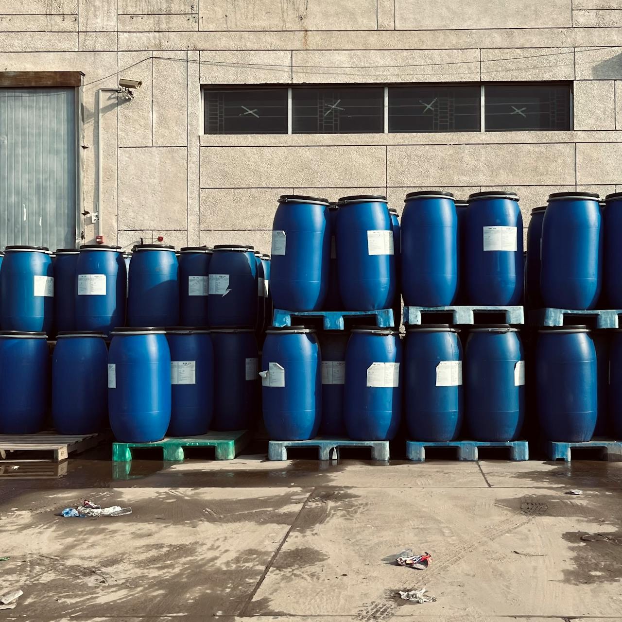 An array of blue barrels sits outside a facility.