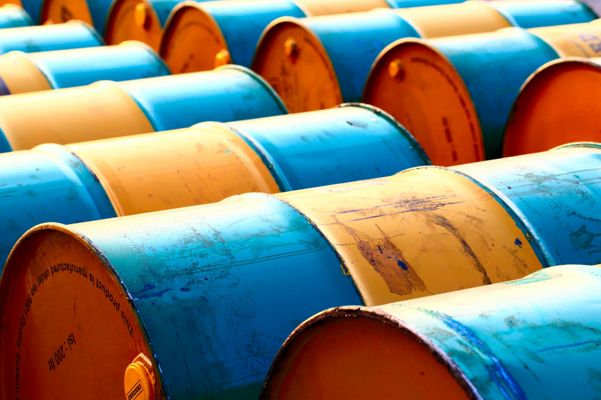 Two rows of blue and yellow metal waste barrels lined up.