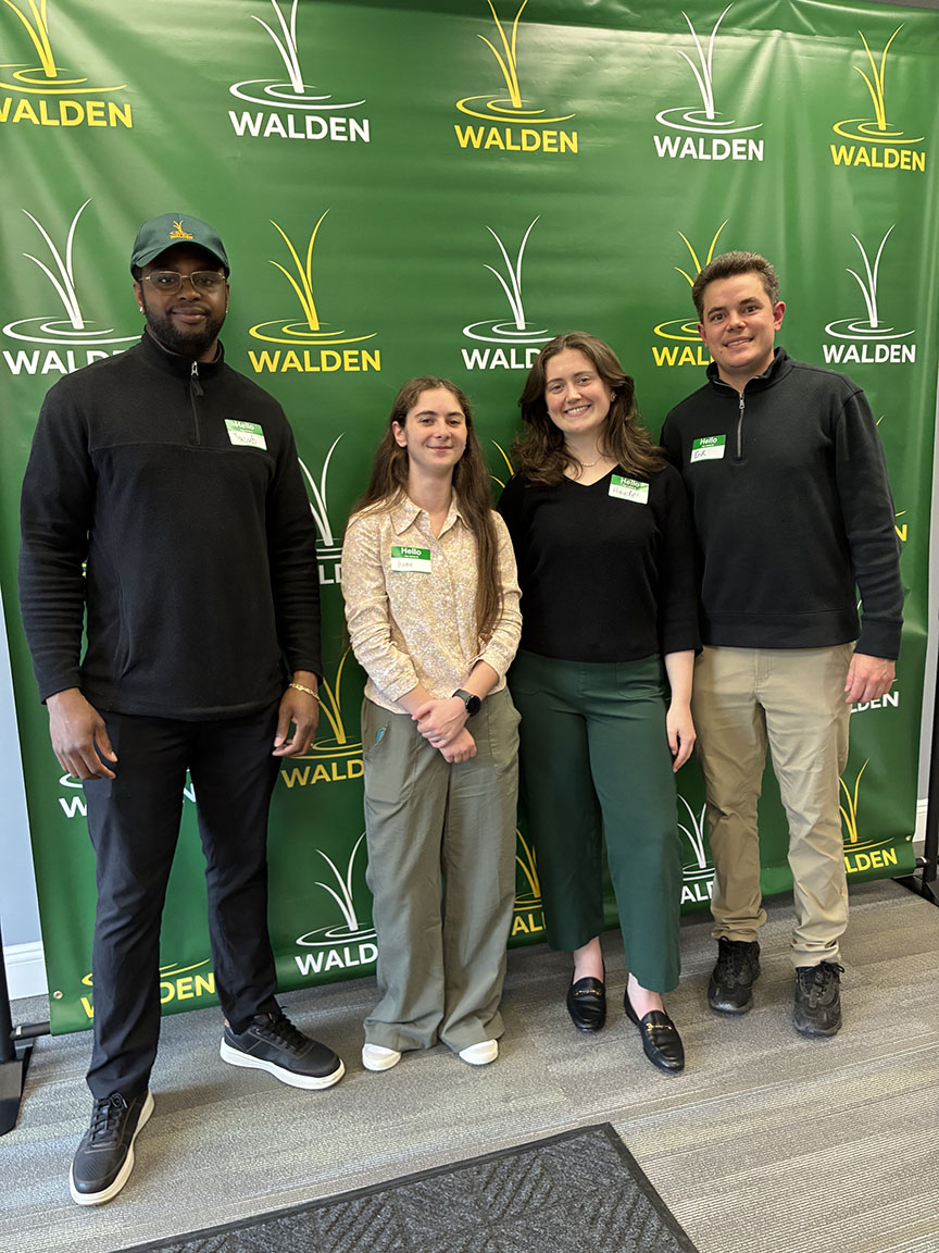 four people stand in front of a green background