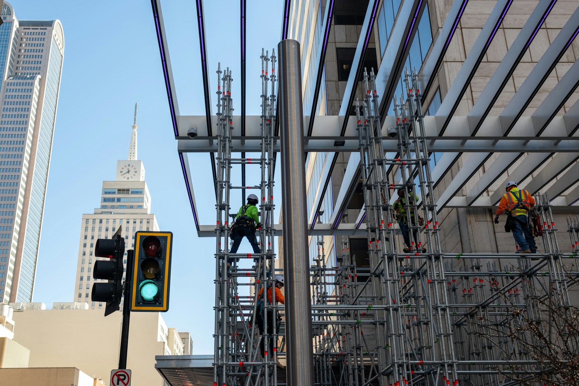 Workers wearing neon vests on scaffolding.