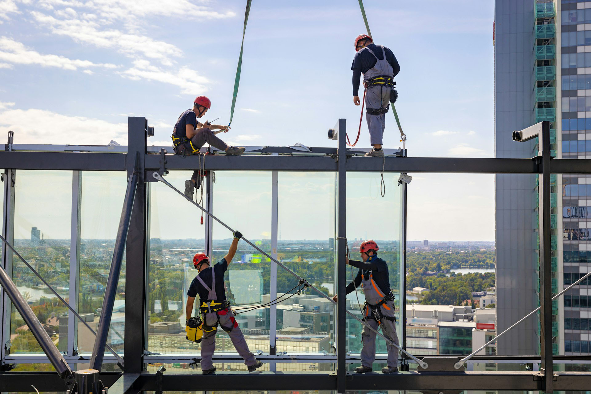 Four construction workers wearing fall protection on a skyscraper.