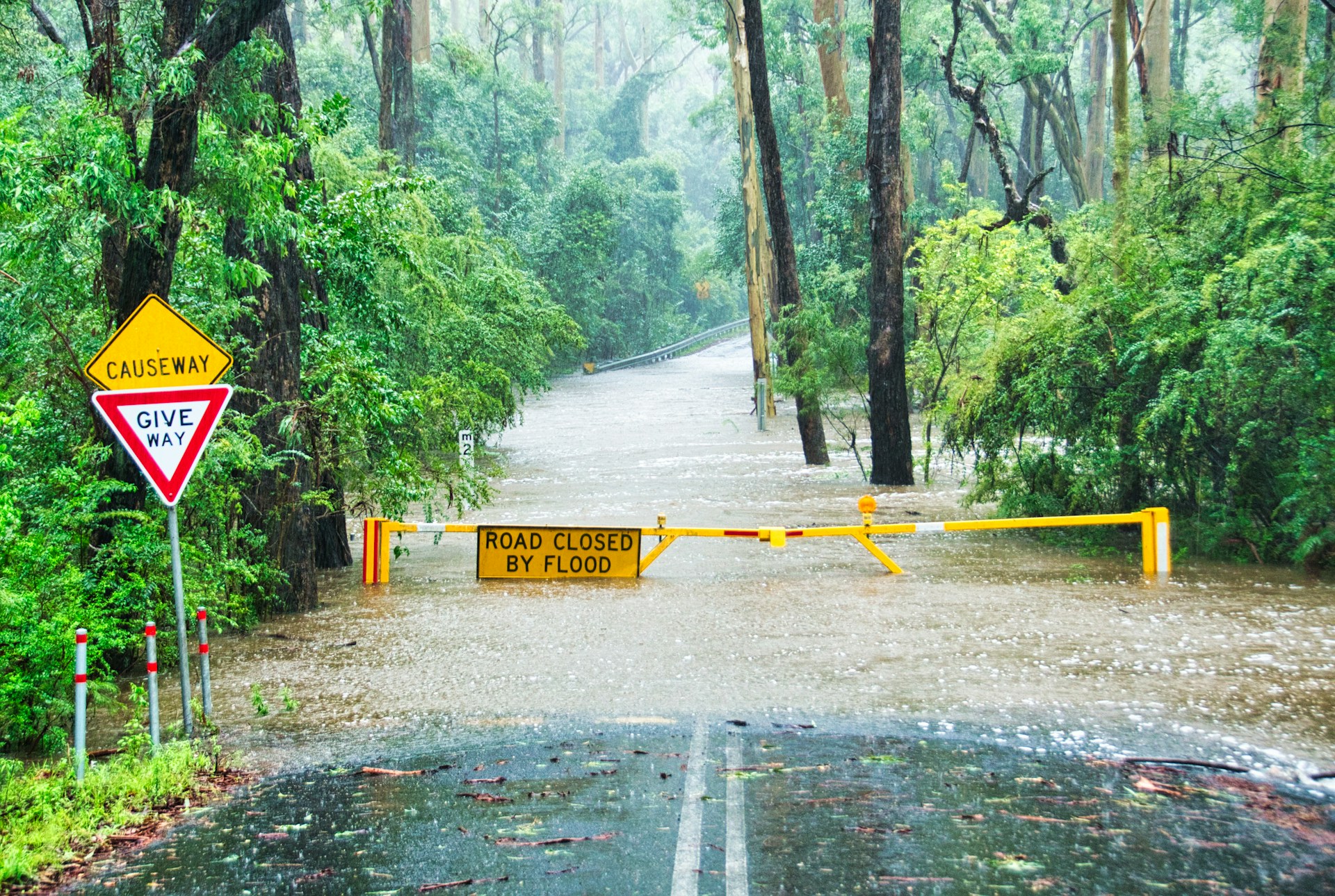 A flooded road blocked with yellow signage.
