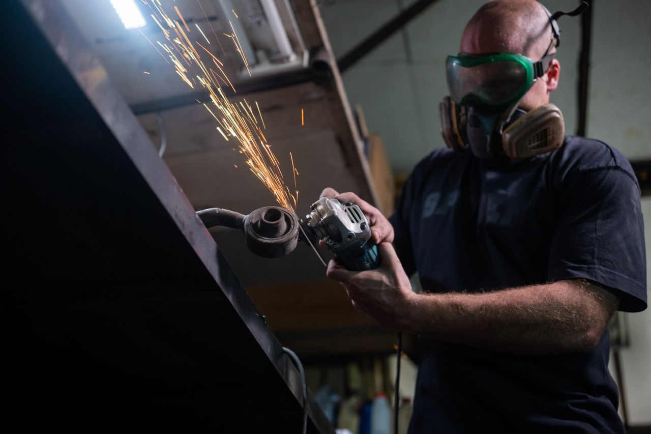 A man wearing a respirator using a grinder.