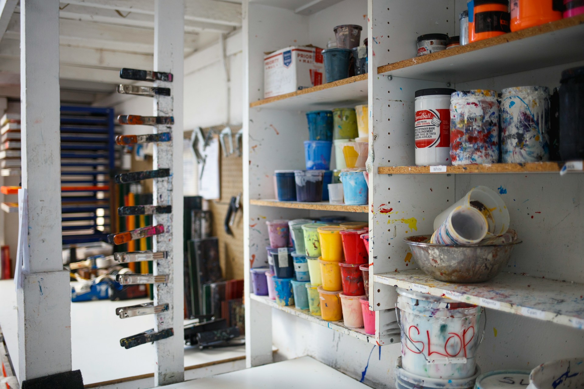 paint buckets on the shelves of an art classroom
