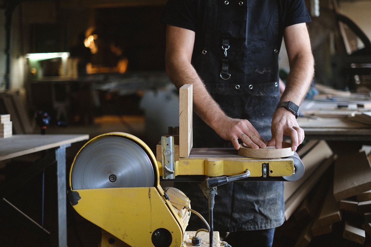sanding a piece of wood on a belt sander
