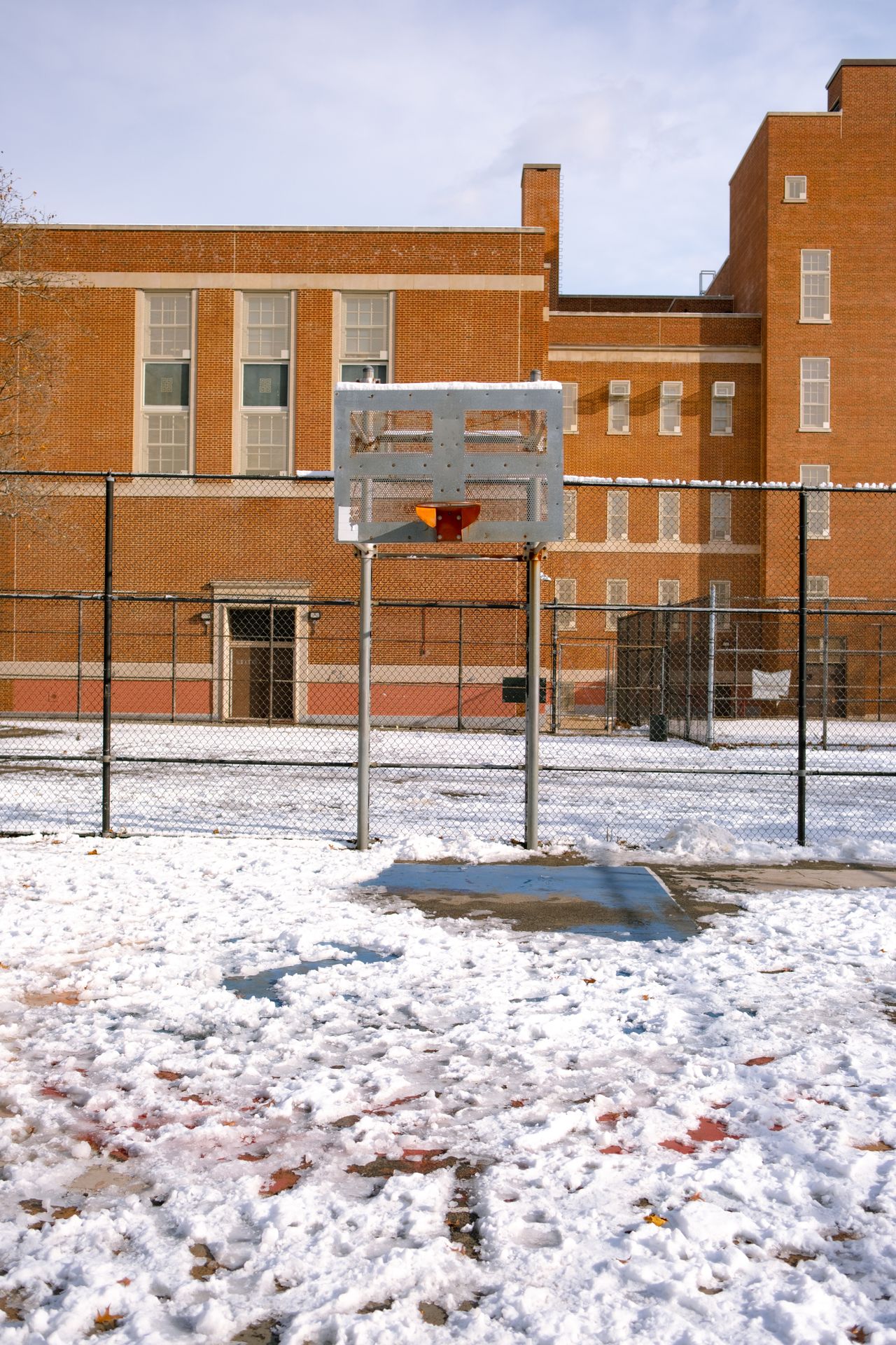 a snowy basketball court outside a school