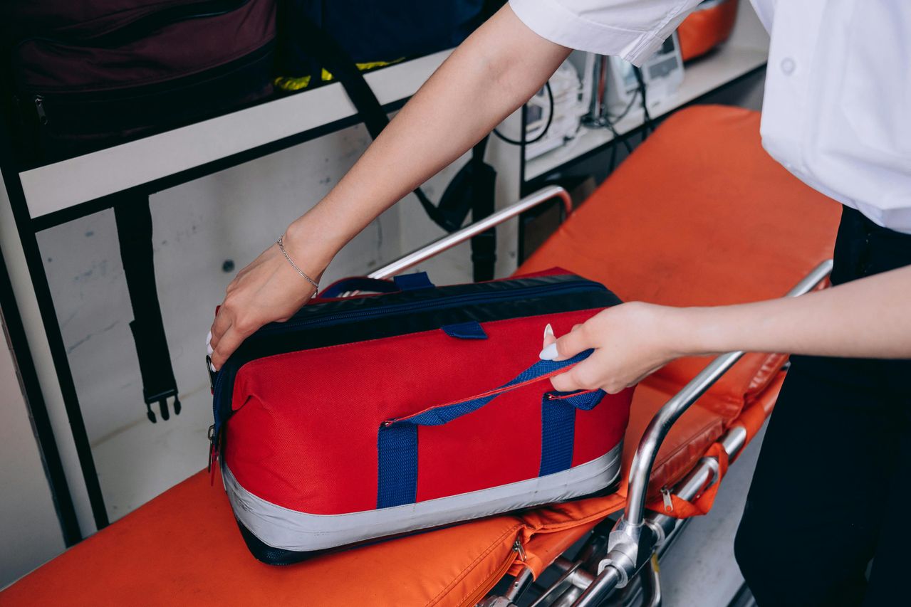 paramedic reaching into a red first aid kit