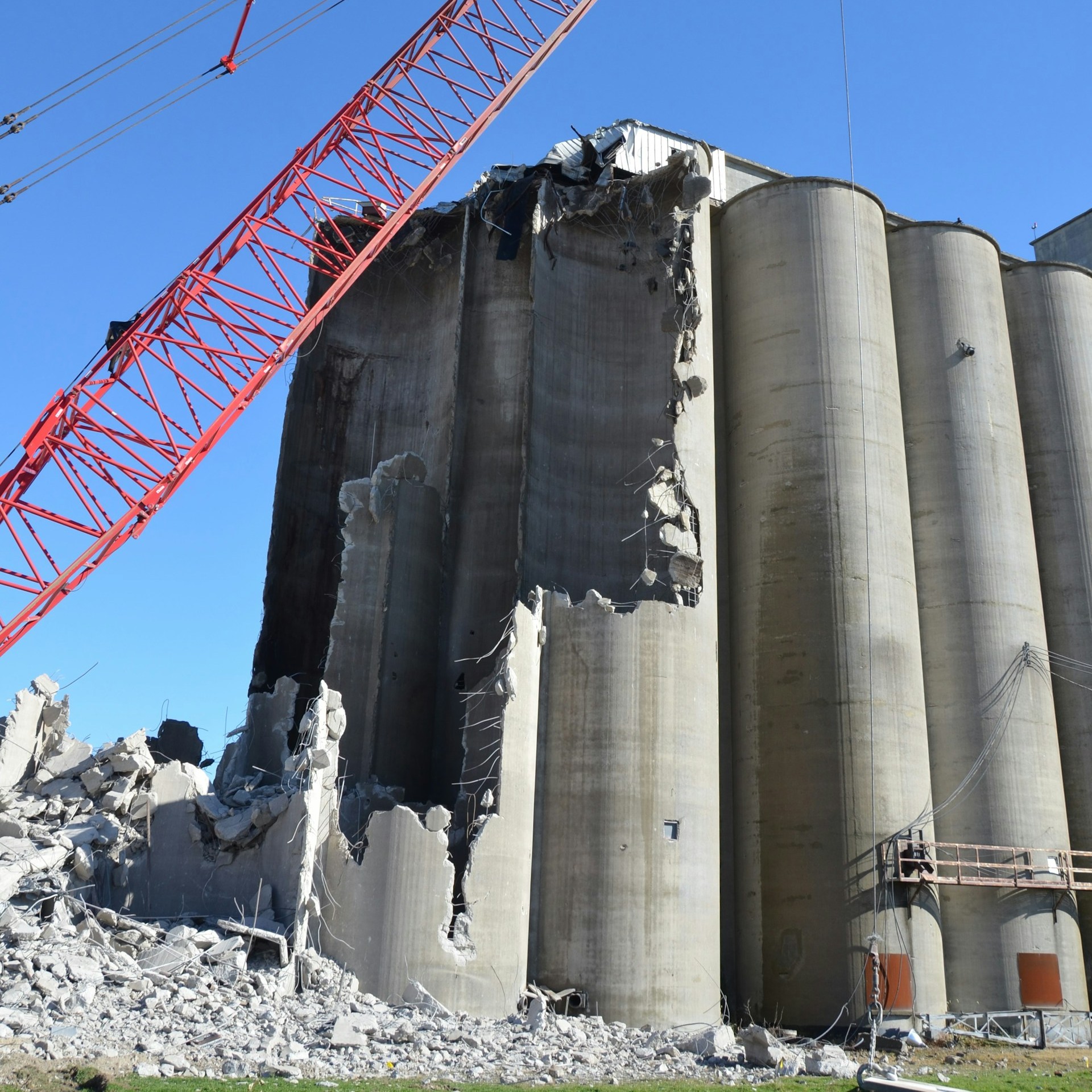 a red crane in front of partly demolished storage tanks